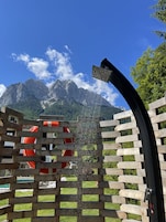 Una cerca de madera con un elemento acuático y un flotador salvavidas rojo en primer plano, con un paisaje montañoso al fondo.