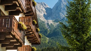 Una cabaña de montaña con balcones de madera y vistas a una cadena montañosa.
