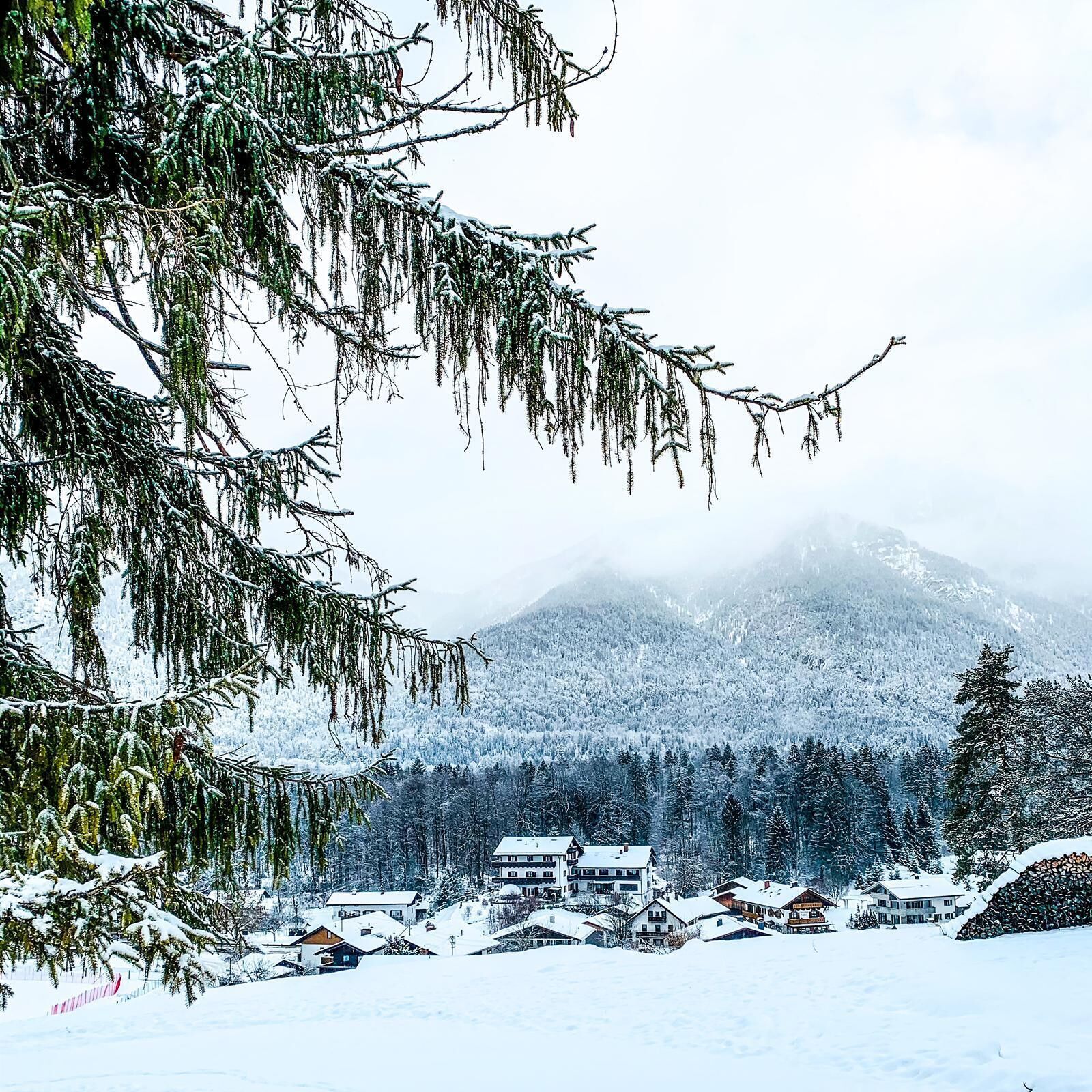 Un paisaje montañoso cubierto de nieve con un grupo de casas en primer plano.
