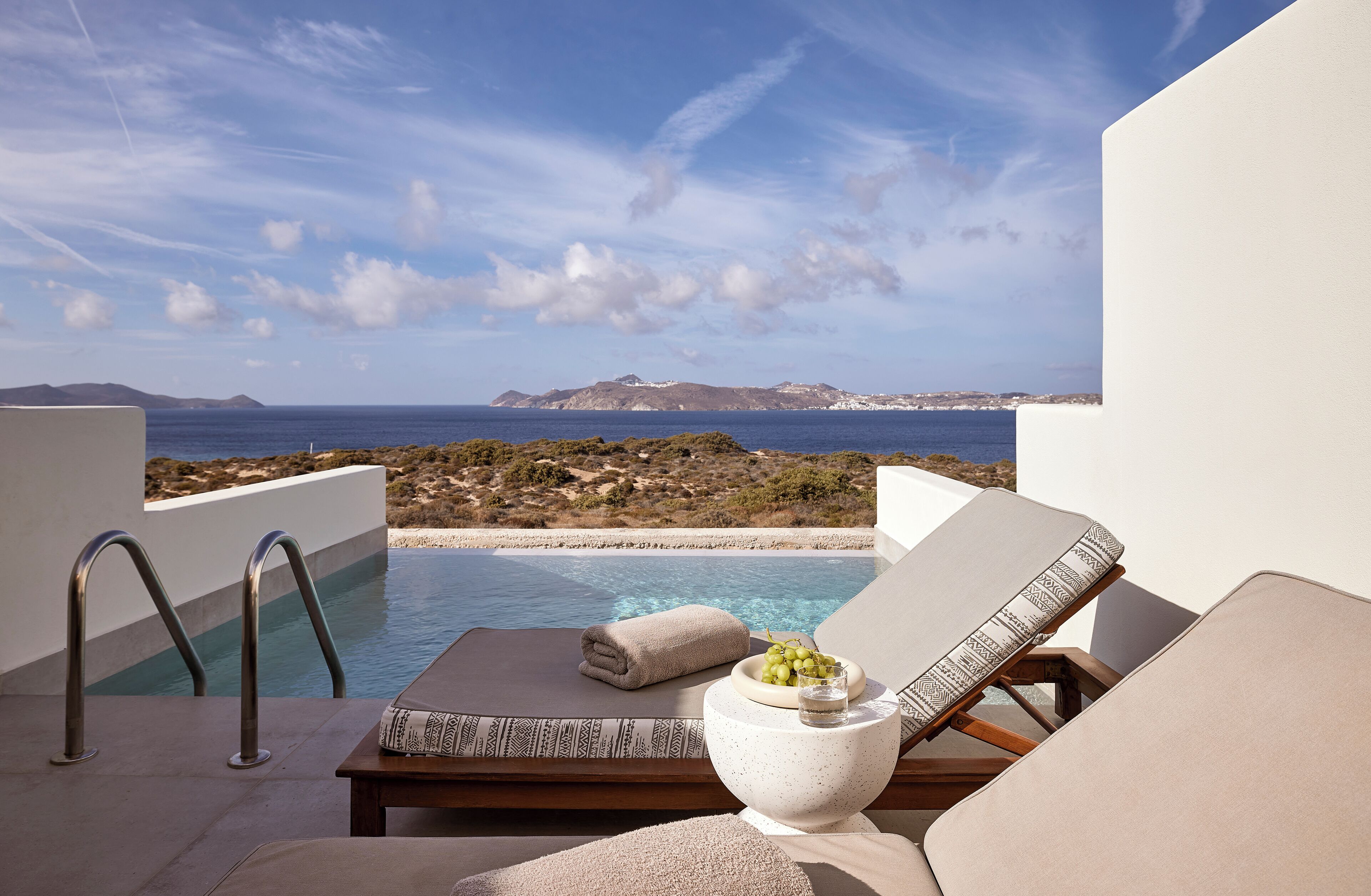 Un espace aménagé au bord de la piscine, avec des chaises longues, un saladier de raisins et une serviette.