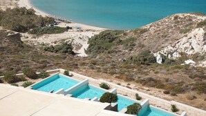 A pool area with a view of a beach and a body of water. -  Hotel Milos Sea Resort (Milos)