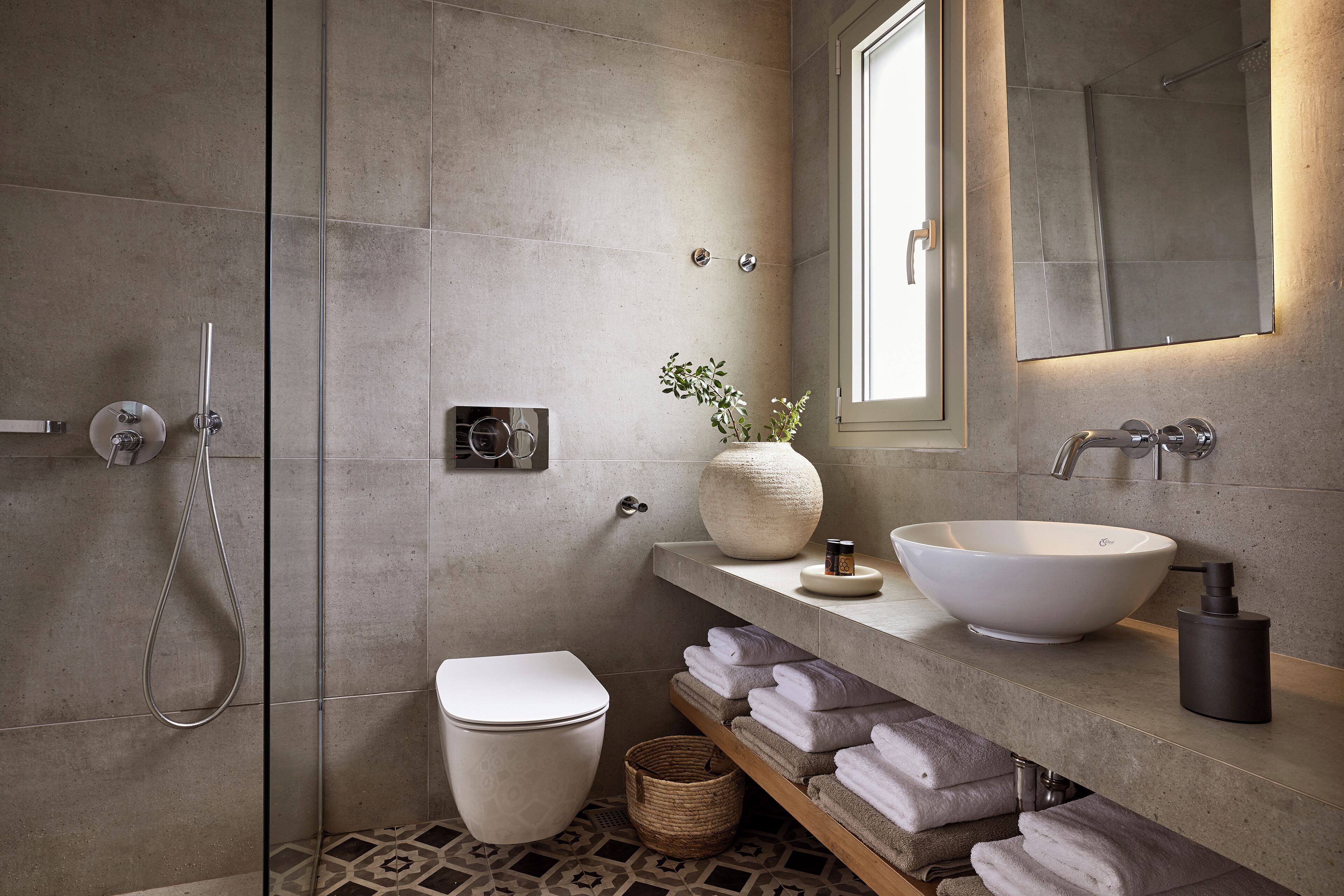 Une salle de bain moderne avec un grand lavabo blanc, des toilettes, une douche et un miroir au-dessus du lavabo.