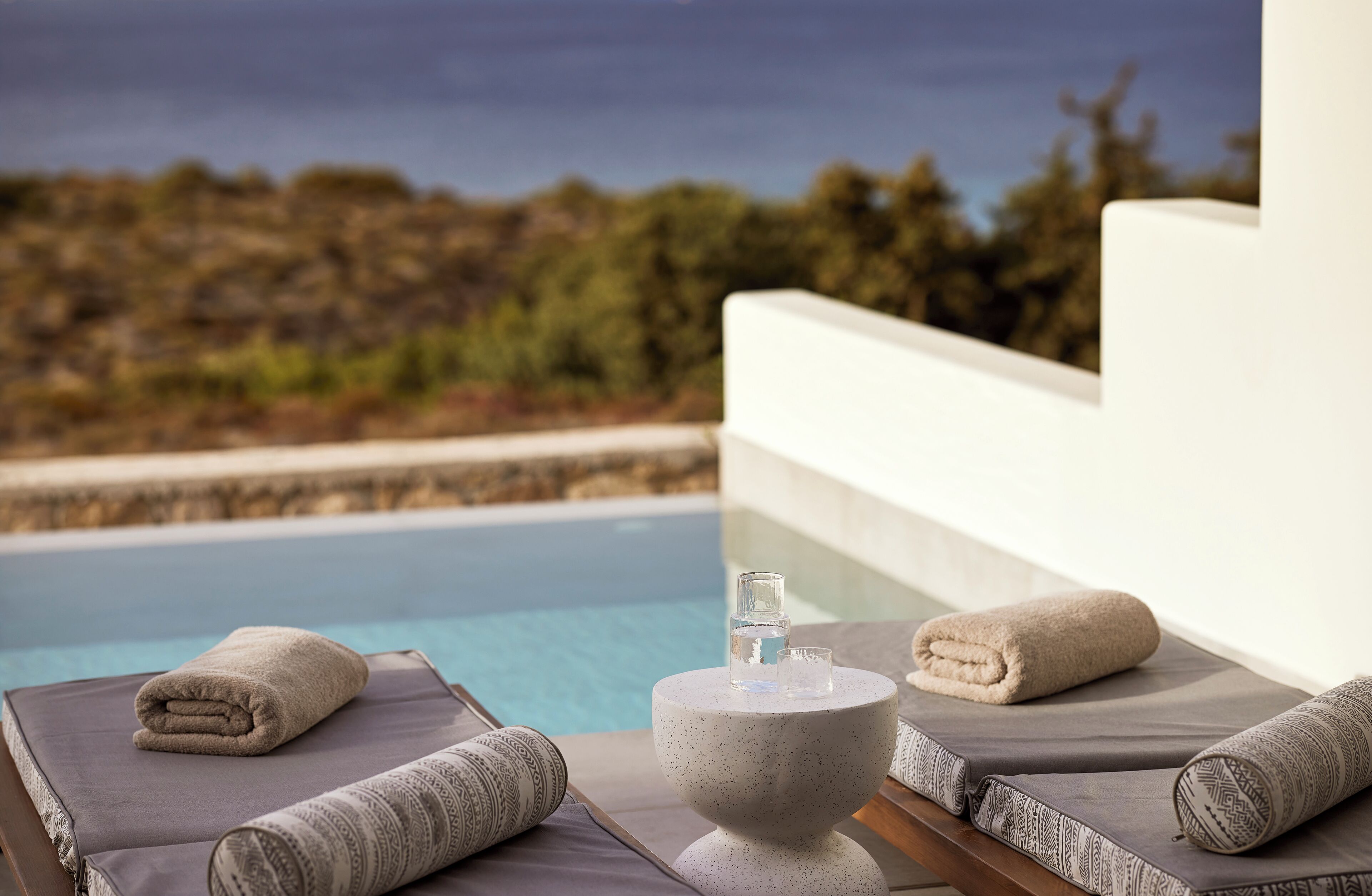 A poolside area with lounge chairs, towels, and a water bottle on a table.