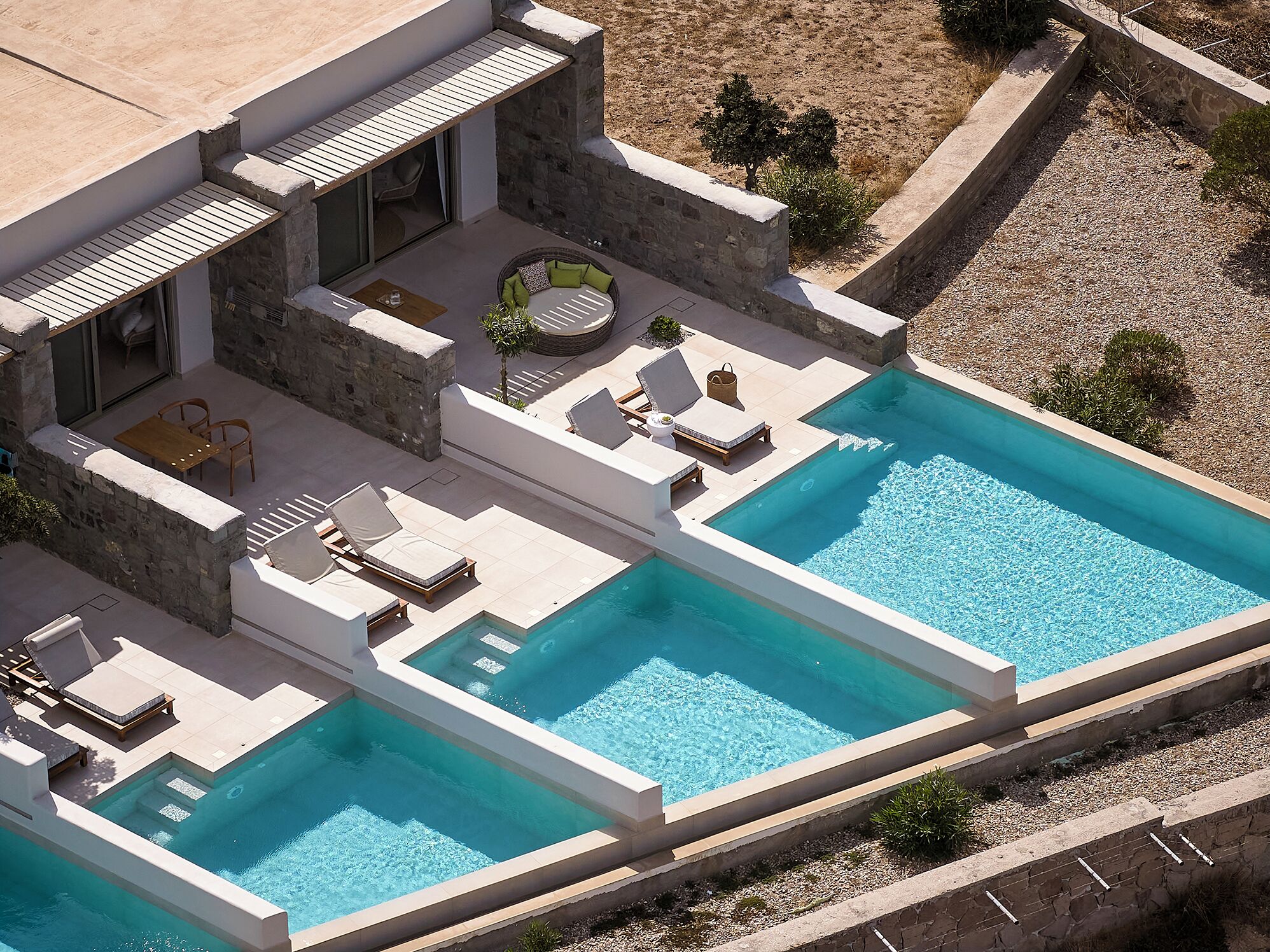 A modern house with a large rectangular swimming pool, outdoor seating area, and a stone exterior.