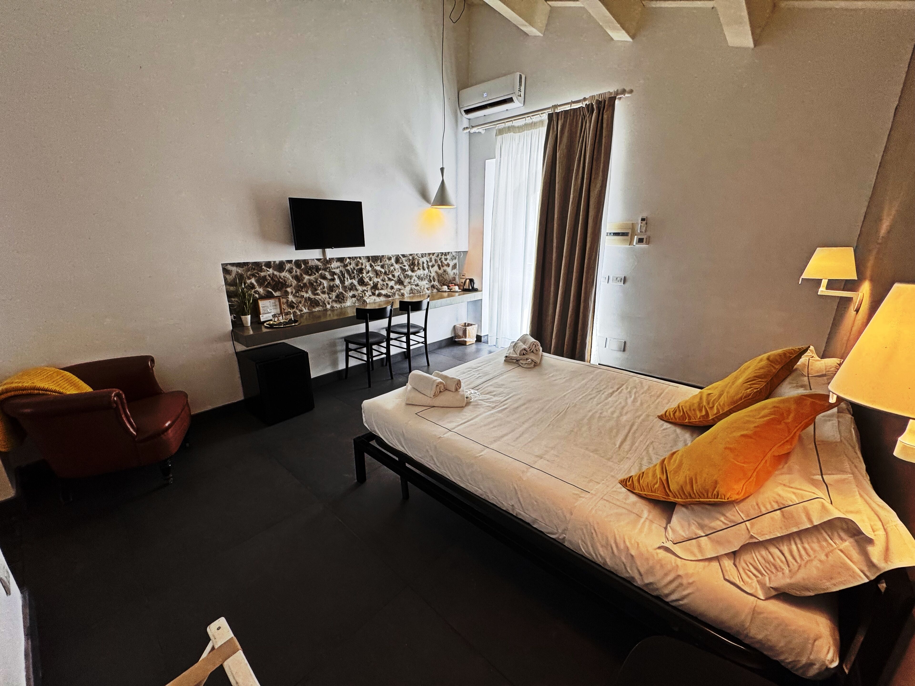 Ein Hotelzimmer mit Bett, Schreibtisch, Stuhl, Fernseher und Klimaanlage.