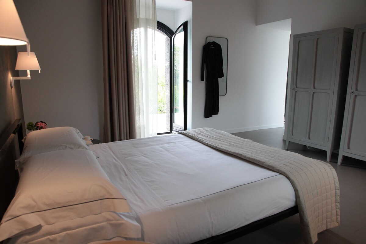 A hotel room with a bed, a wardrobe, and a window with curtains.