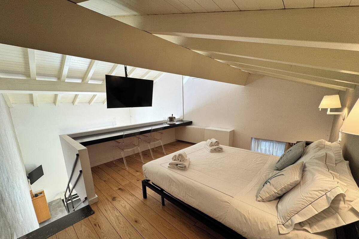 Un dormitorio con cama, escritorio, televisor y lámpara.
