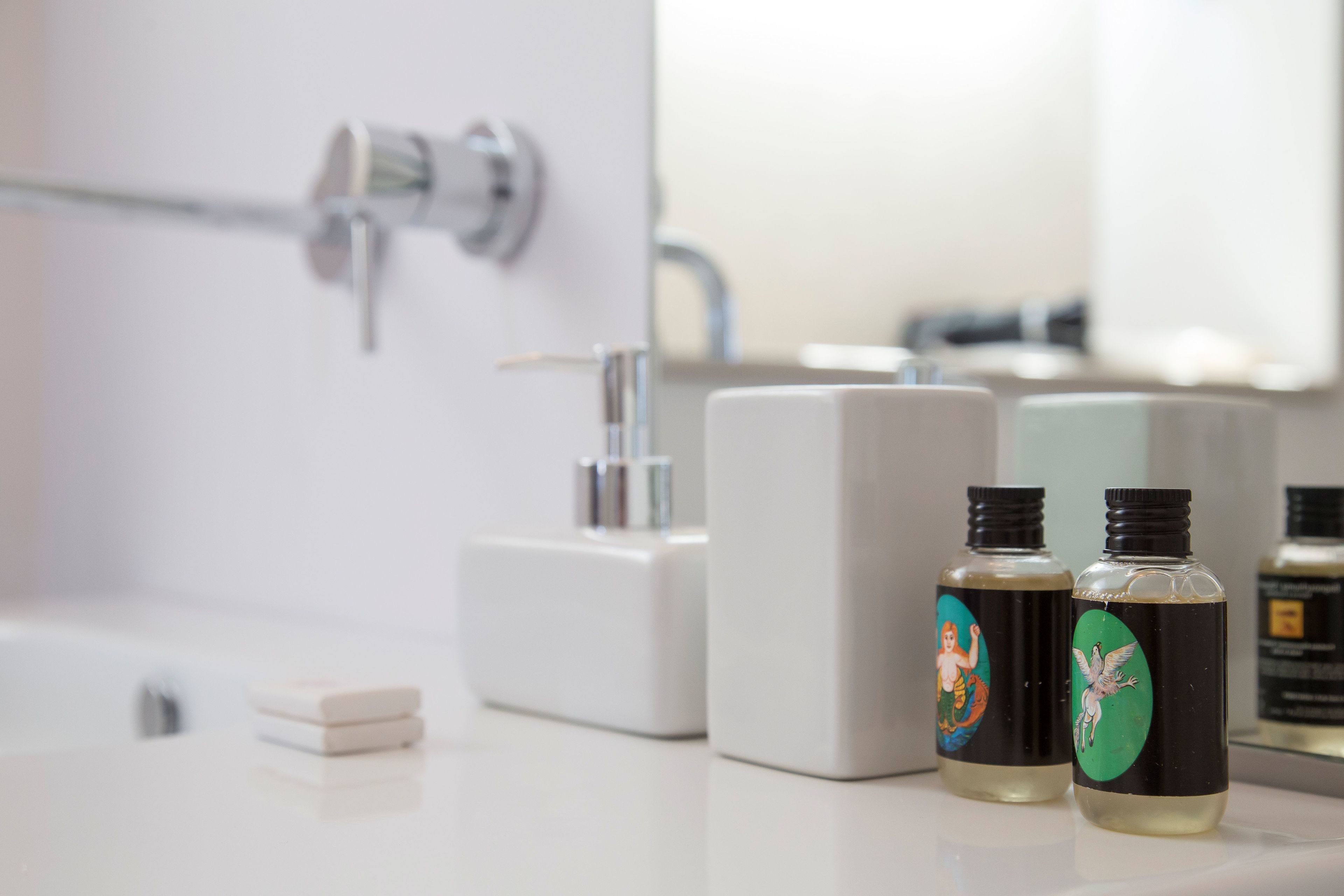 Una encimera de baño con dos botellas de jabón líquido y un jabonero.