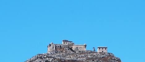 A historic building complex on a hill with multiple structures, including a prominent central building and smaller buildings around it.
