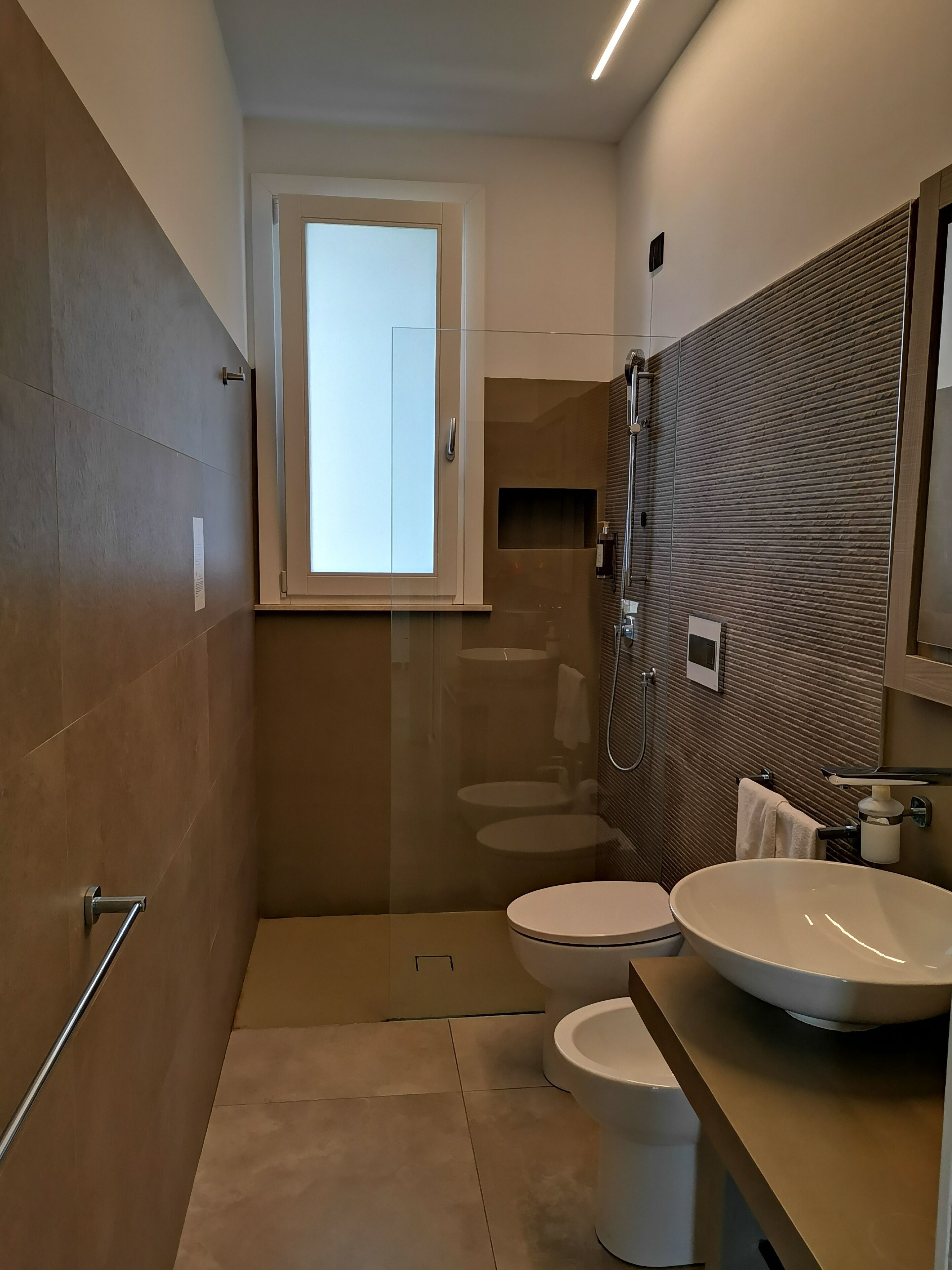 A modern bathroom with two toilets, a large sink, and a shower.