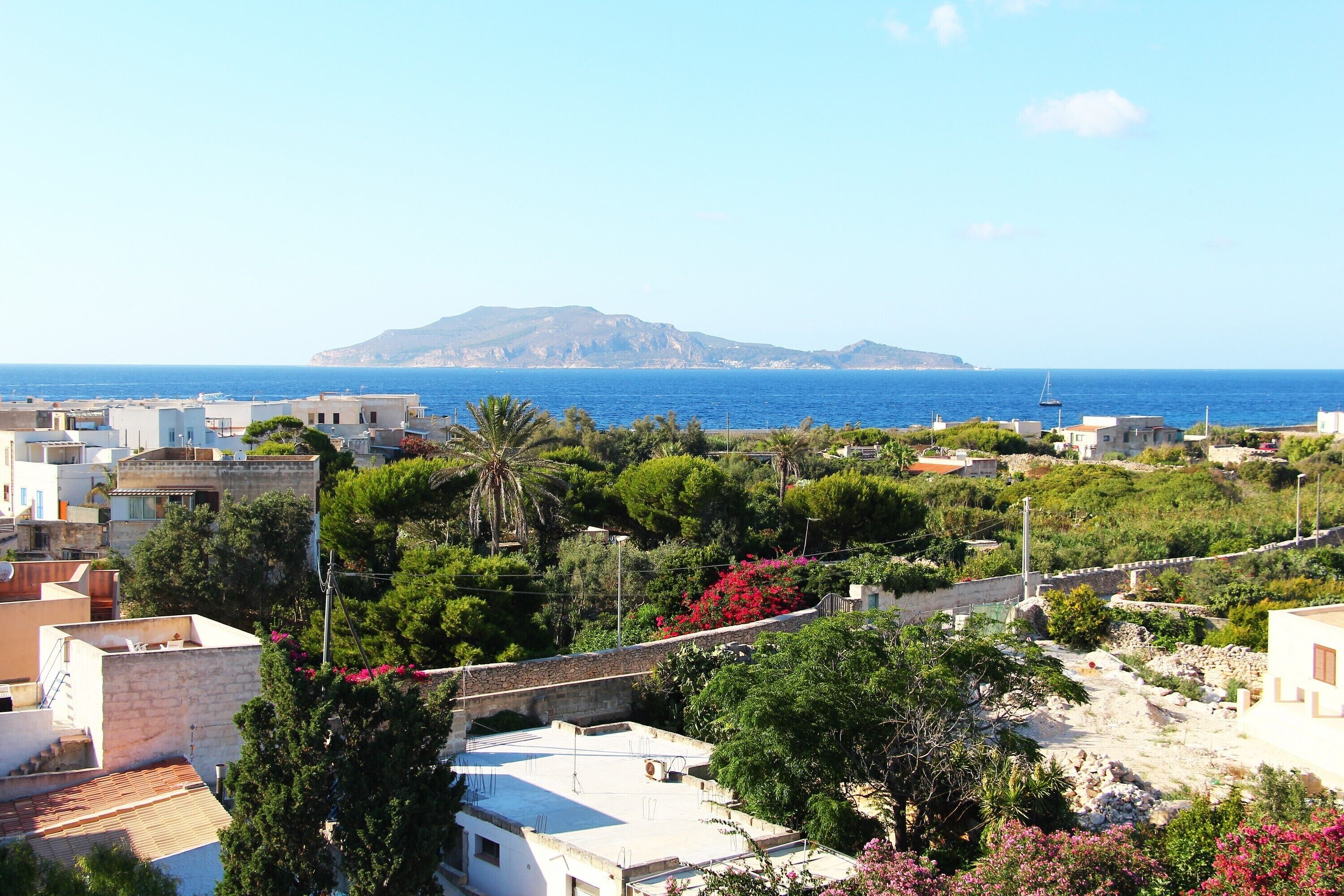 Un pueblo costero con edificios, un puente y vistas al mar y una isla distante.
