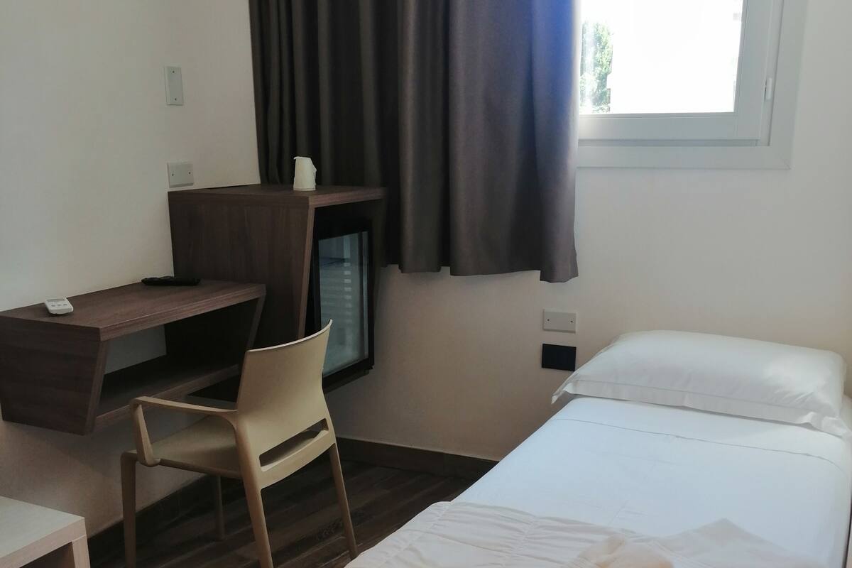 A bedroom with a bed, a desk, and a chair.