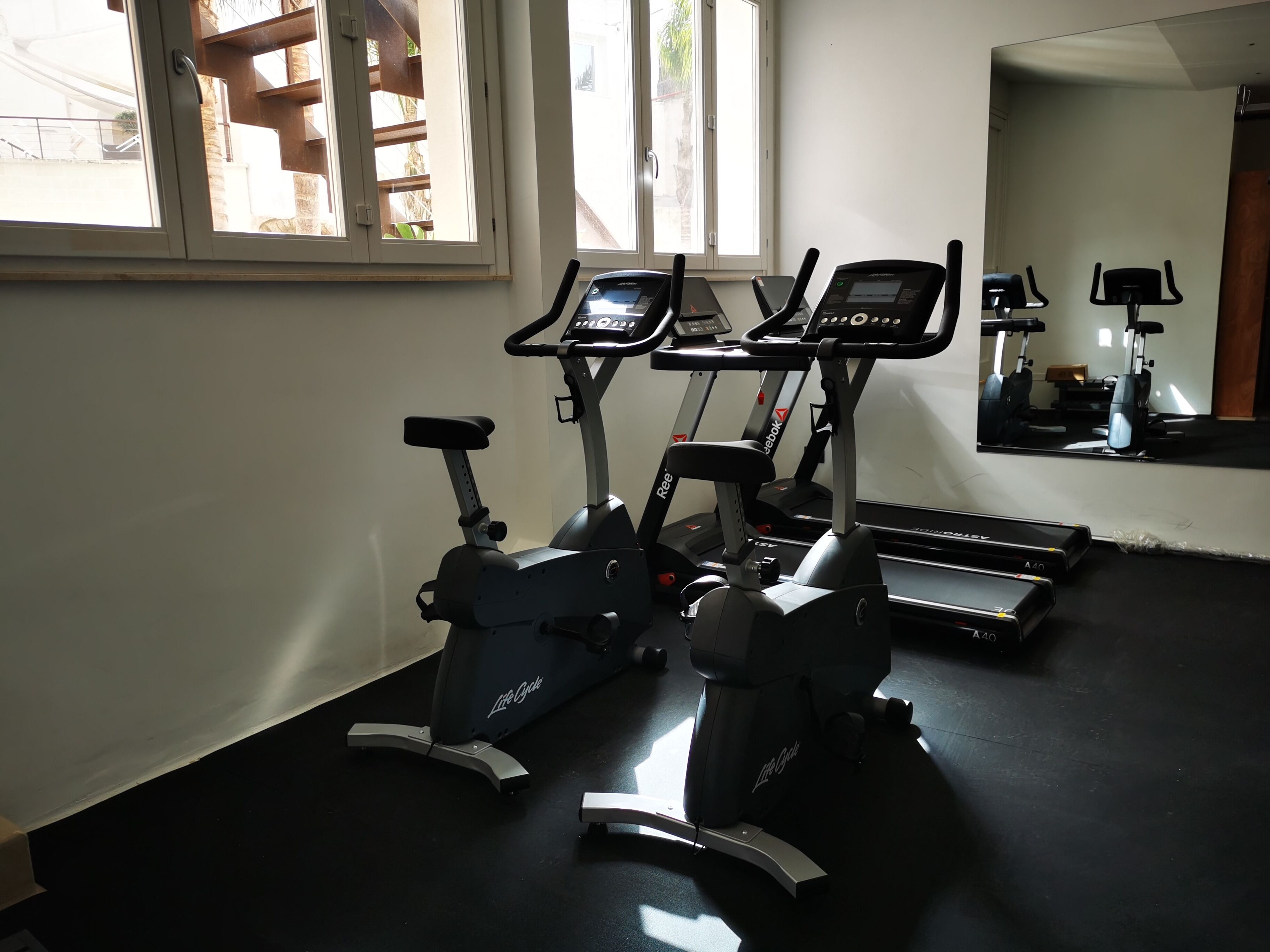 Un gimnasio con dos bicicletas estáticas y una cinta de correr.