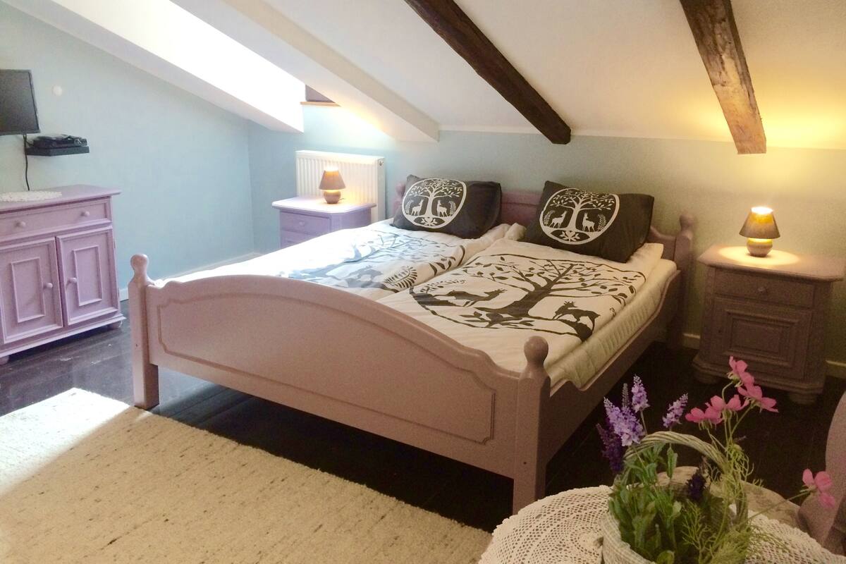 A bedroom with a bed, bedside tables, a dresser, and a window.