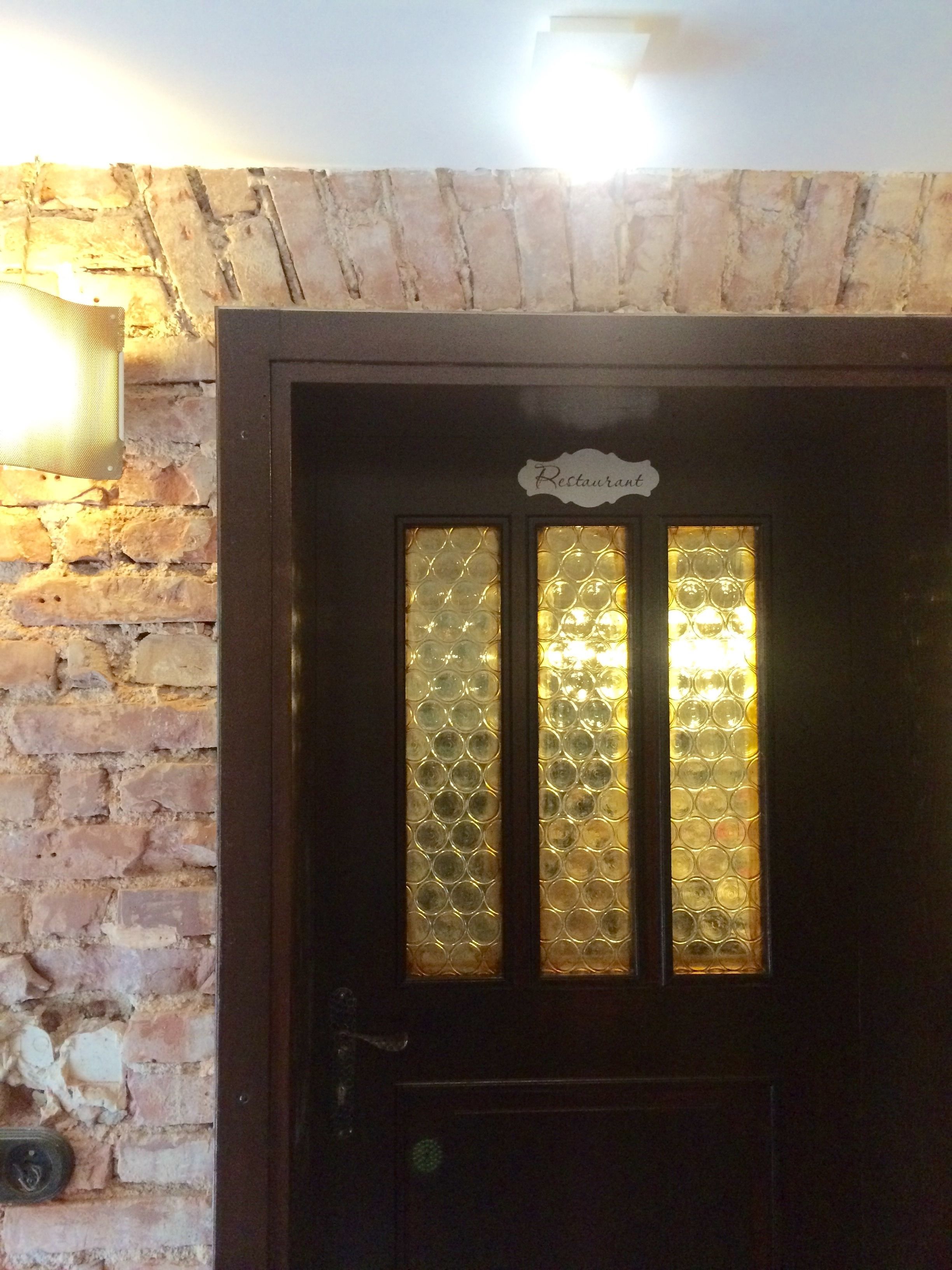 Una puerta de madera oscura con un panel de vidrio esmerilado y un letrero que dice "Restaurant" encima.
