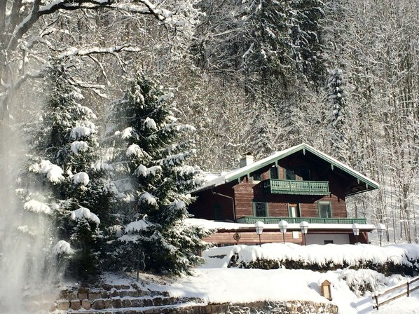 Una cabaña de madera con balcón, rodeada de árboles cubiertos de nieve.