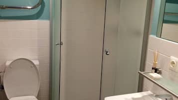 A bathroom with a toilet, a glass-enclosed shower, and a sink.