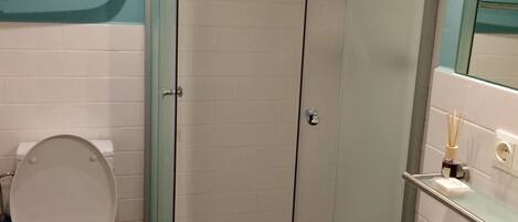 A bathroom with a toilet, a glass-enclosed shower, and a sink.