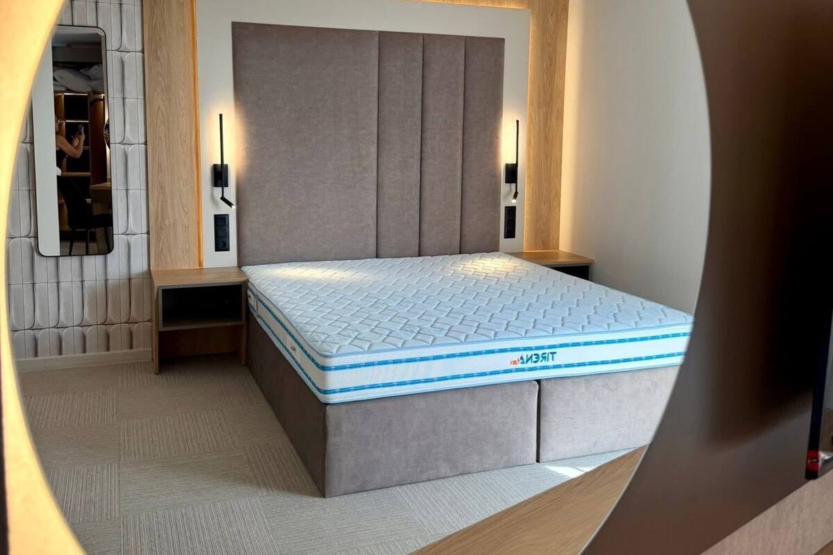 A bedroom with a bed, bedside tables, a mirror, and a wardrobe.