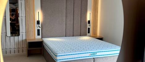 A bedroom with a bed, bedside tables, a mirror, and a wardrobe.