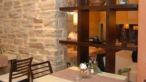Pared de piedra, muebles de madera y estantes con adornos en un comedor.