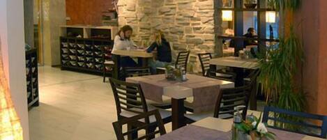 A restaurant with stone walls, tables, and chairs.