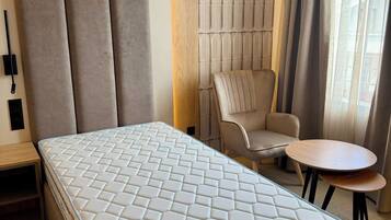 Una camera d'albergo con un letto grande, un divano, un tavolino e una sedia.