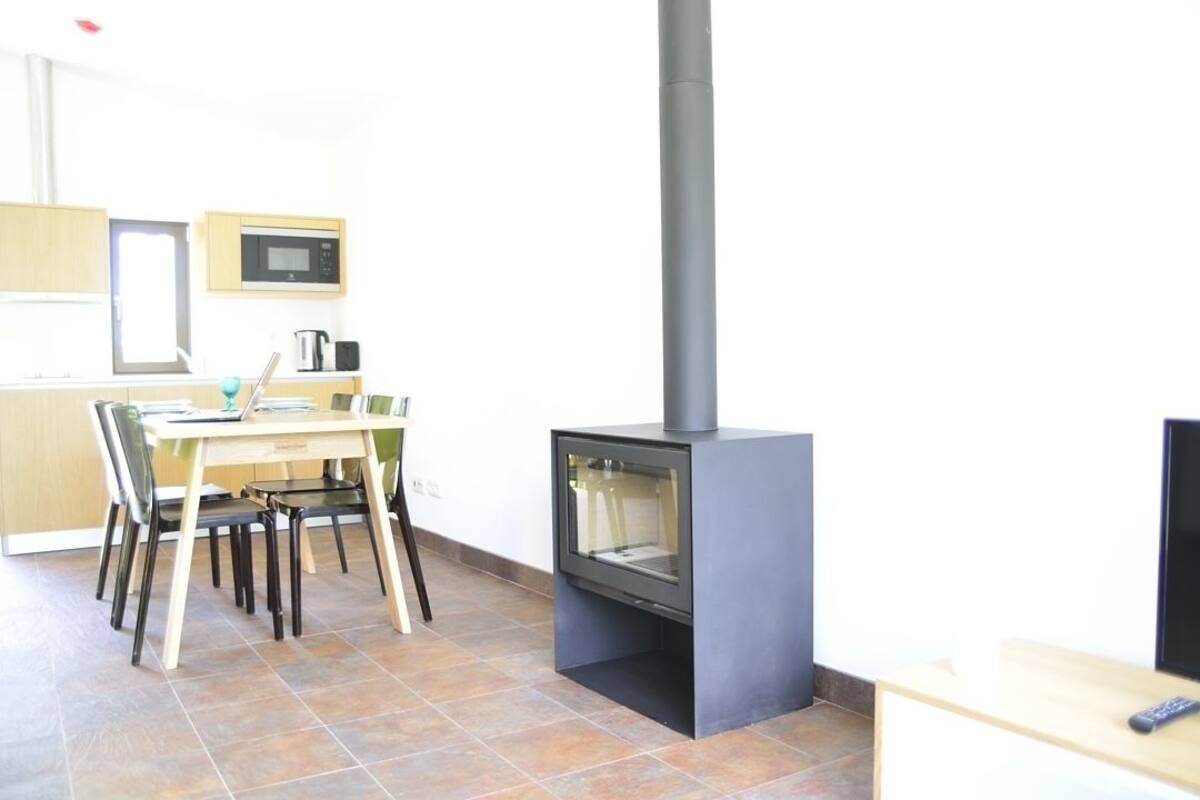 A modern kitchen with a built-in stove, wooden dining table, chairs, and a microwave on the wall.