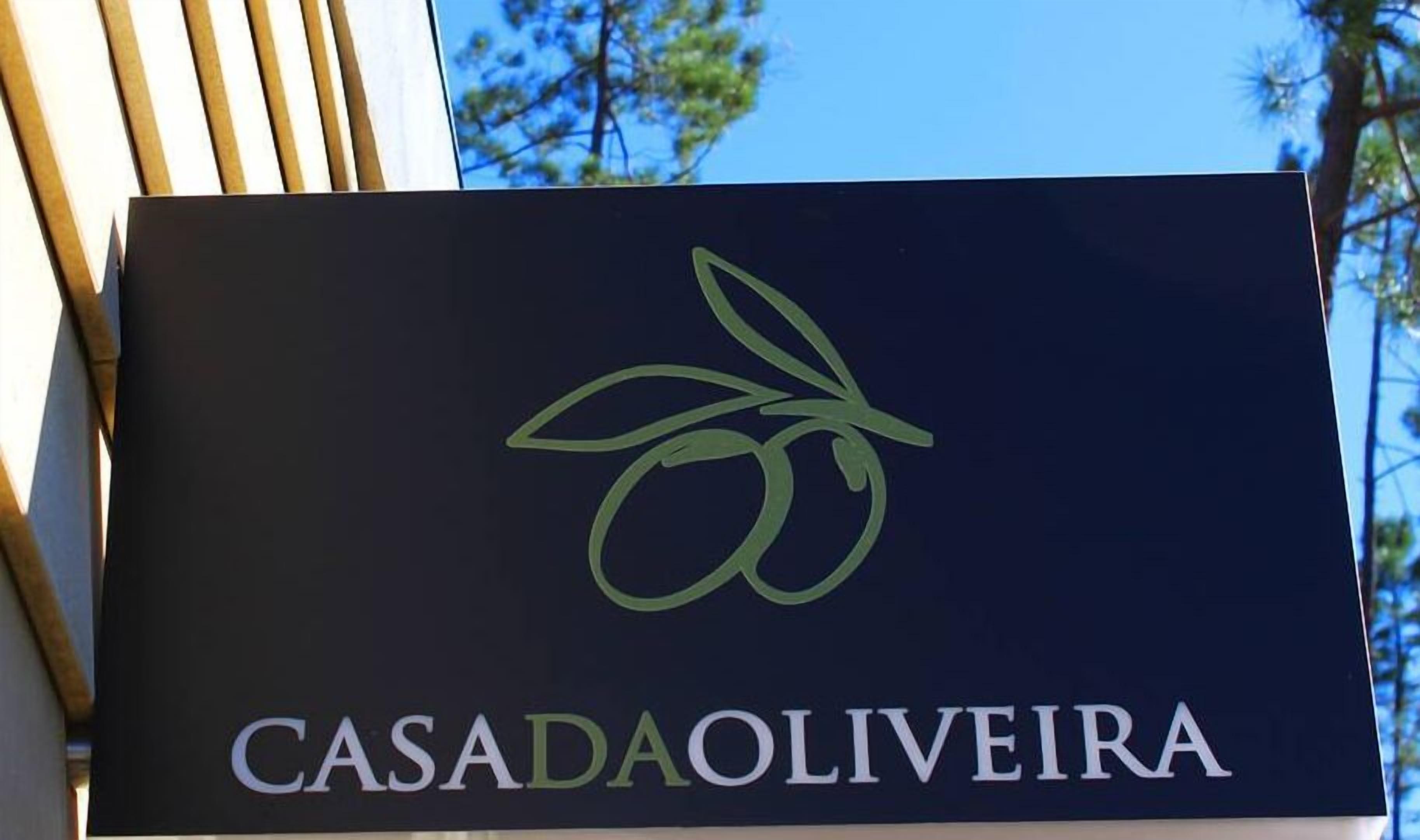 A sign with the text "CASADAOLIVEIRA" and a stylized olive branch logo.