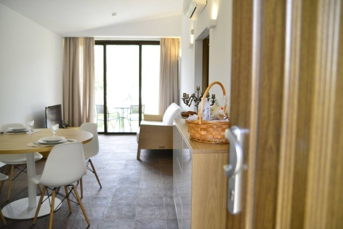 A modern hotel room with a dining area, a balcony, and a kitchenette.