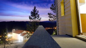 A modern building with a sign reading "CASADOLINHO" at night, featuring a paved pathway leading to the entrance.