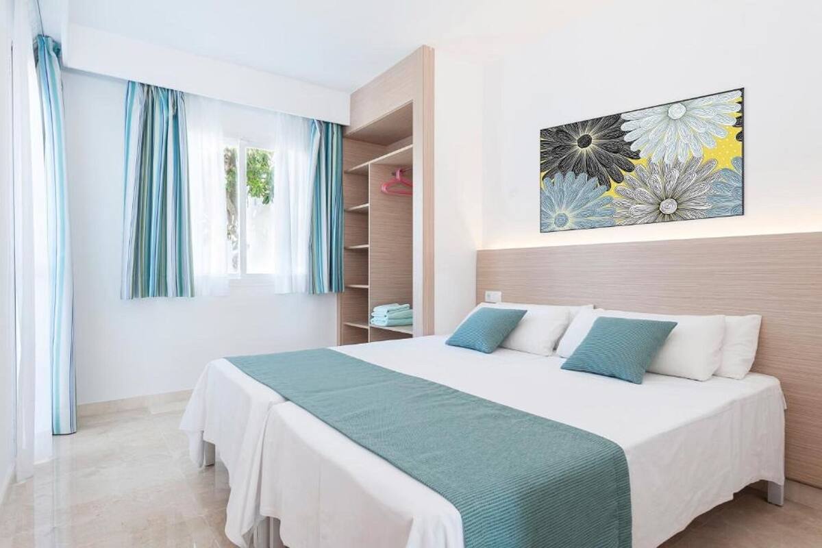 A bedroom with a bed, a wardrobe, and a wall-mounted artwork.