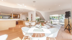 A modern hotel lobby with a central seating area, a reception desk, and a view of the outdoors. - A10 Solecito Apartamentos (Alcúdia)