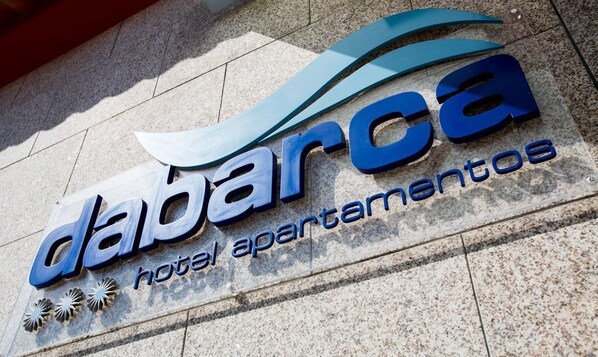 Un letrero para 'Dabarca Hotel Apartamentos' con un diseño moderno y un elemento gráfico en forma de ola.