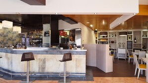 Un área de bar moderna con mostrador, taburetes y estantes llenos de botellas.