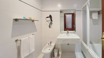 Un baño con bidé, lavabo, espejo y ducha.