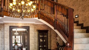 Un amplio vestíbulo con candelabro, escalera y comedor.