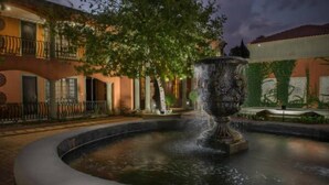 Un patio con una fuente, un árbol y un edificio con balcones.