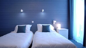 Habitación de hotel con dos camas, una mesita de noche y una lámpara.