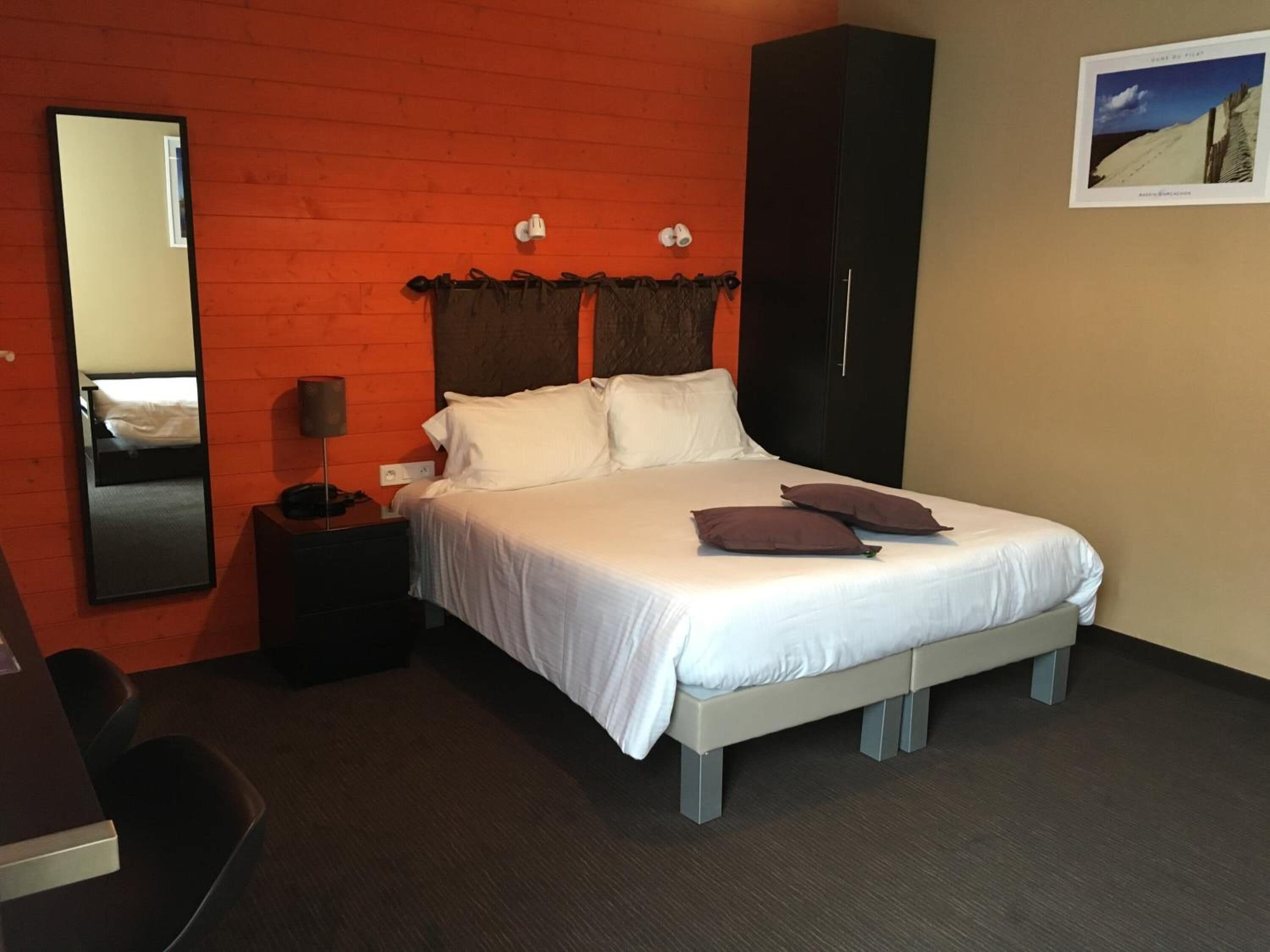 Una camera da letto ordinata con un letto, un armadio, un comodino e una sedia.