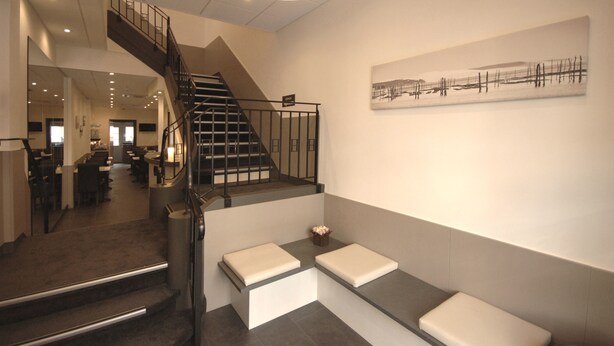 Un interior moderno con una escalera, un área de estar y obras de arte en la pared.
