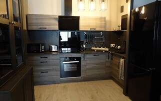 A modern kitchen with dark wood cabinetry, a built-in oven, a coffee maker, and a black refrigerator.