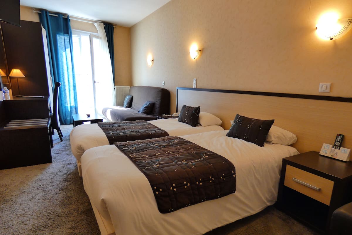 Une chambre d’hôtel avec deux lits, un bureau, une chaise et une lampe.