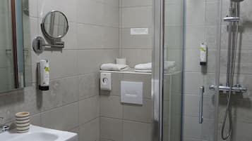 A modern bathroom with a glass-enclosed shower, a toilet, and a sink with a mirror.