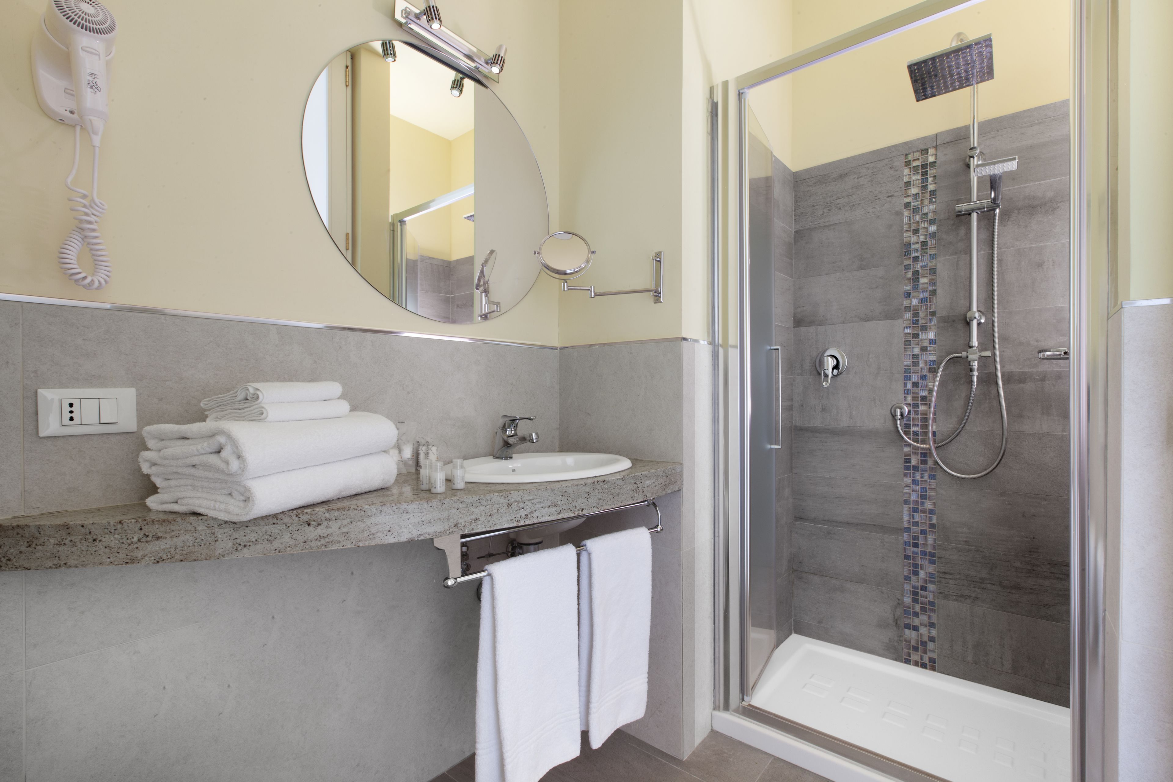 A bathroom with a sink, mirror, and a glass-enclosed shower.