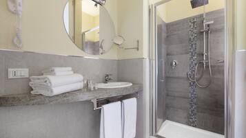A bathroom with a sink, mirror, and a glass-enclosed shower.