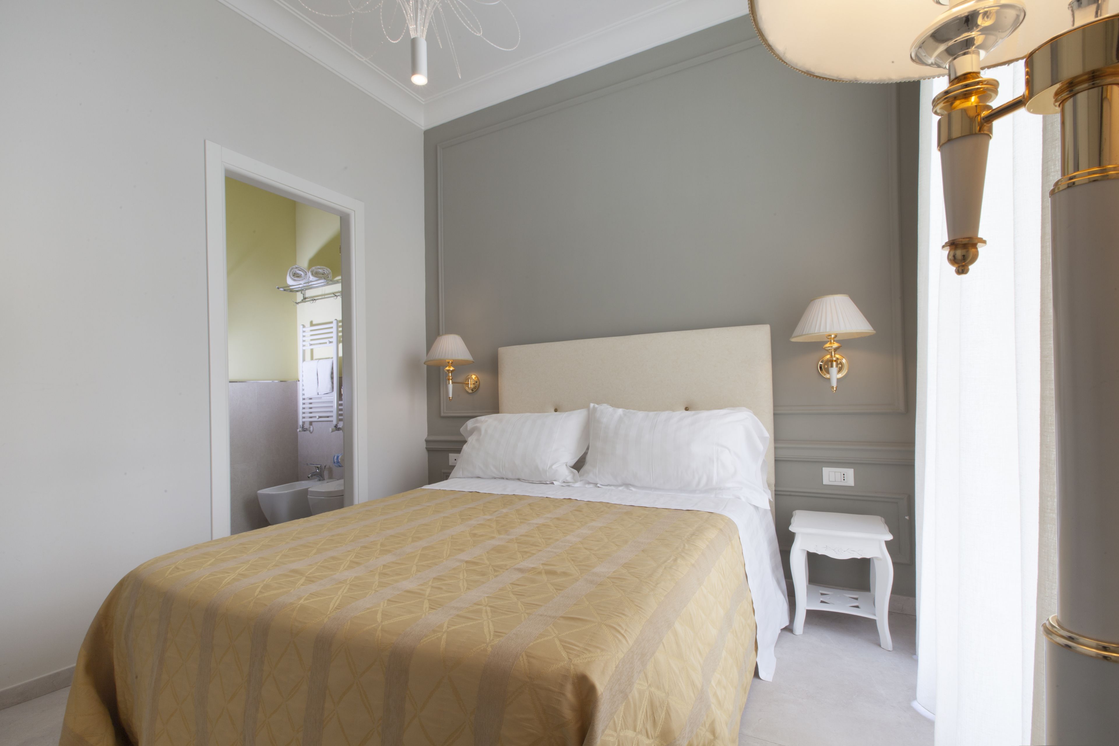 A neatly arranged bedroom with a large bed, bedside lamps, and a small nightstand.