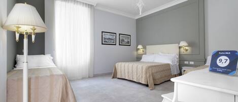 A hotel room with two beds, a desk, and a chandelier. There are two framed pictures on the wall.