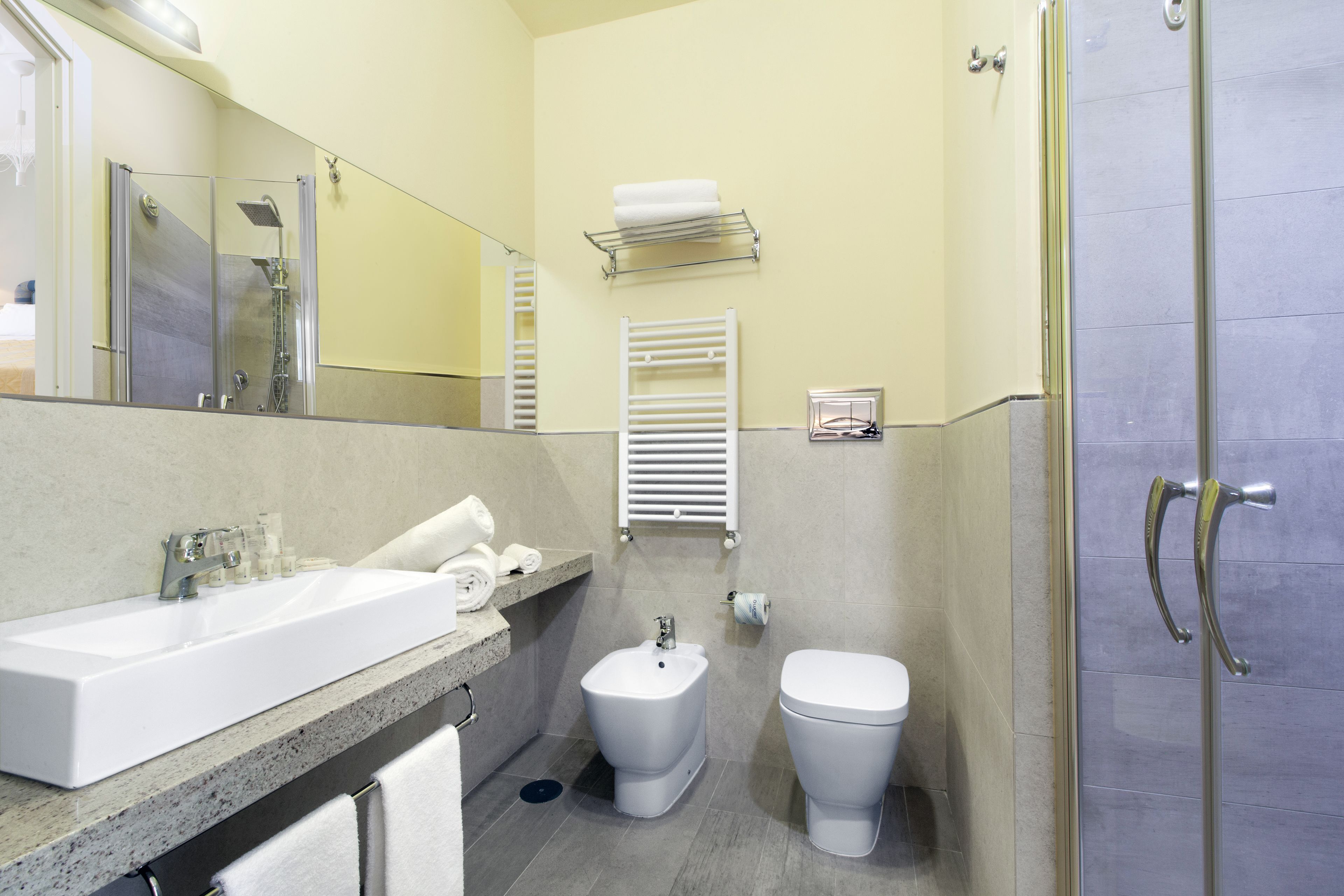 Un baño moderno con un lavamanos grande, un bidé, un inodoro y una cabina de ducha de vidrio.
