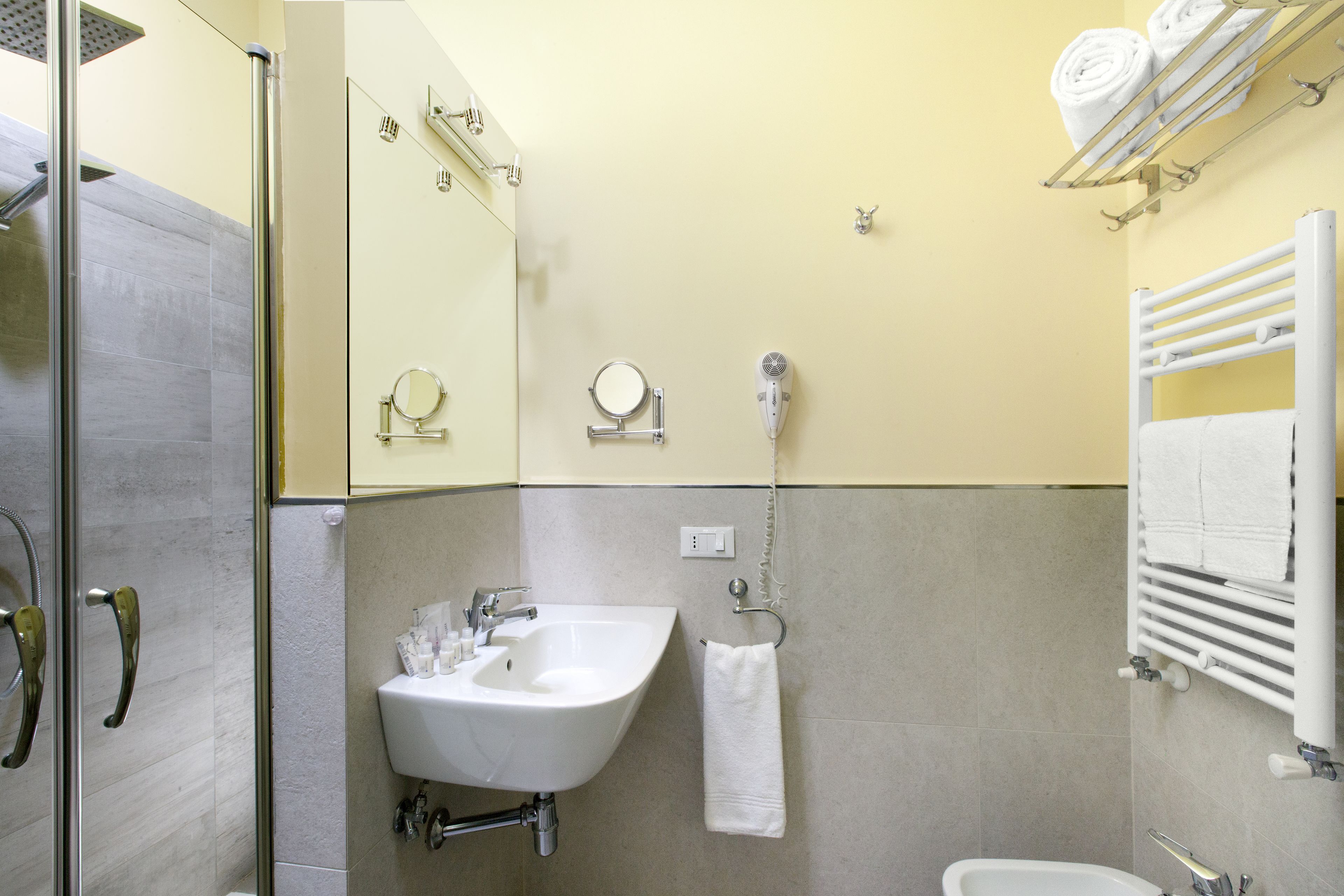 Une salle de bain équipée d’un lavabo, d’un miroir, d’un porte-serviettes et d’une douche.